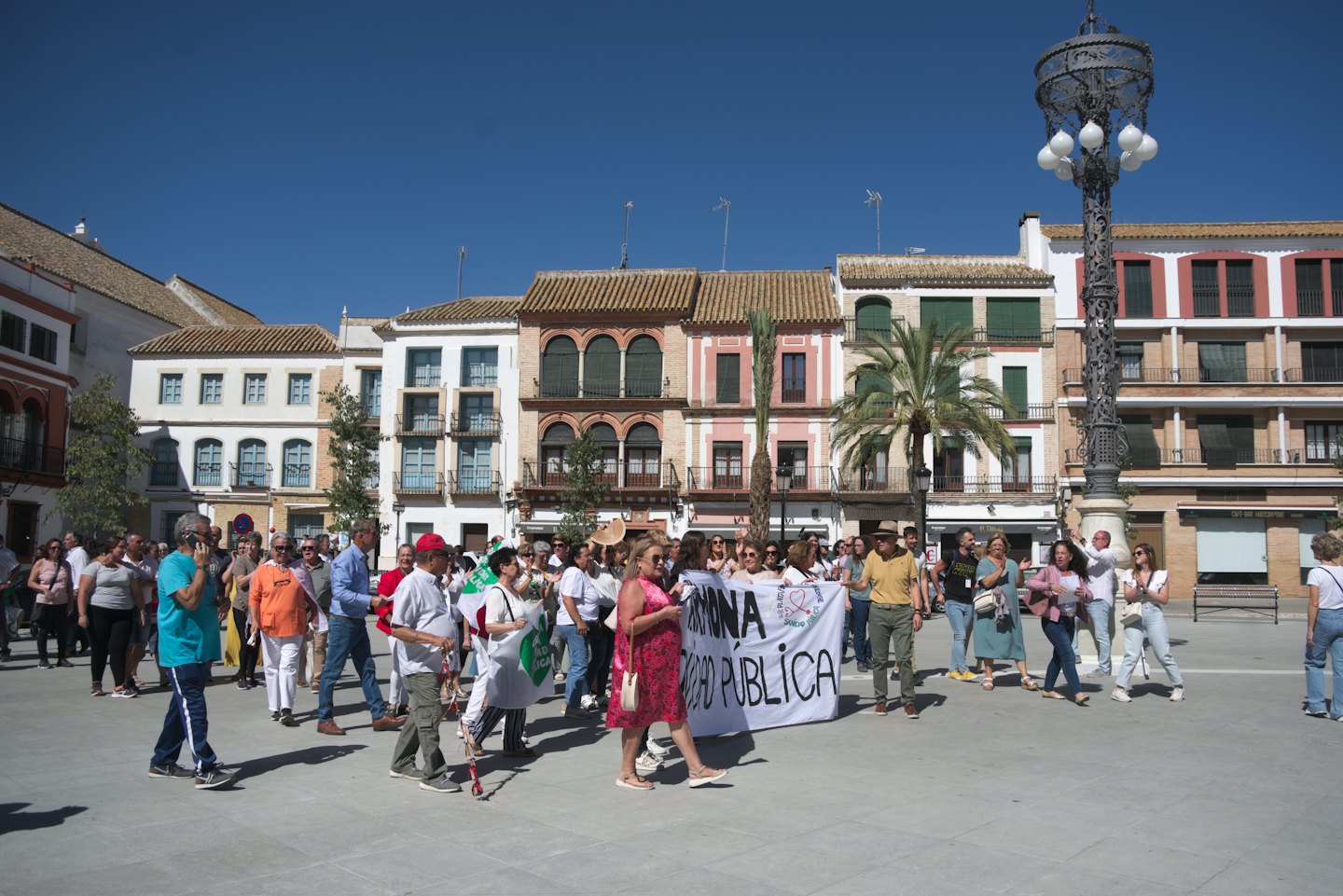 People carry a public health banner through a town square.